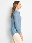 Light blue, semi-sheer long-sleeve collared shirt.  Button cuffs. Shown on a model.