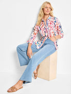 Long-sleeve button-down shirt with abstract pink, blue, and orange pattern on a cream background.