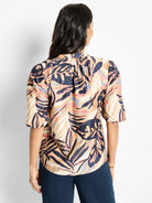 Beige top with dark blue, pink, and light blue leaf print. Puff sleeves.  Shown from the back.
