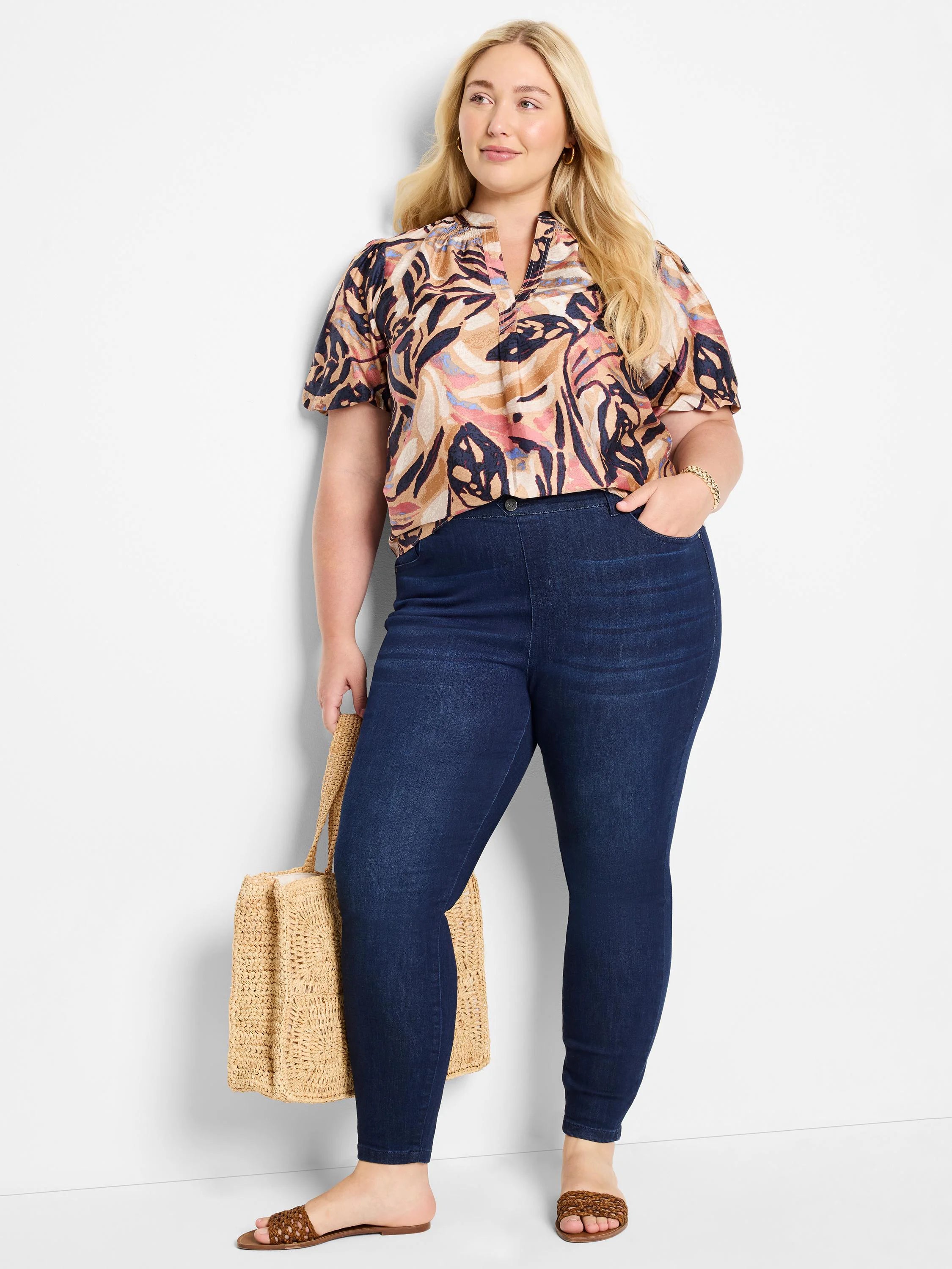 Dark wash denim leggings; model wears a tan, pink, and dark-blue abstract print top.