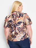 Terracotta top with short sleeves, abstract leaf print in beige,  dark-blue, pink, and light-blue.  V-neck.