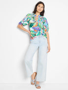 Abstract blue, green, orange, and pink print. Short sleeves, ruffled neckline, and tie detail.