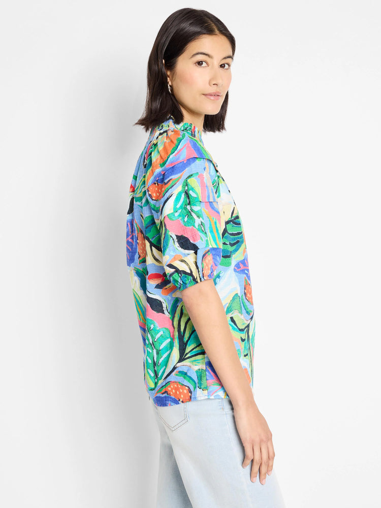 Blue top with vibrant green, orange, and pink abstract leaf print. Short sleeves, slightly puffed.