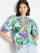 Blue, green, orange, & pink abstract print.  Short sleeves, ruffled shoulders, keyhole neckline with drawstrings.