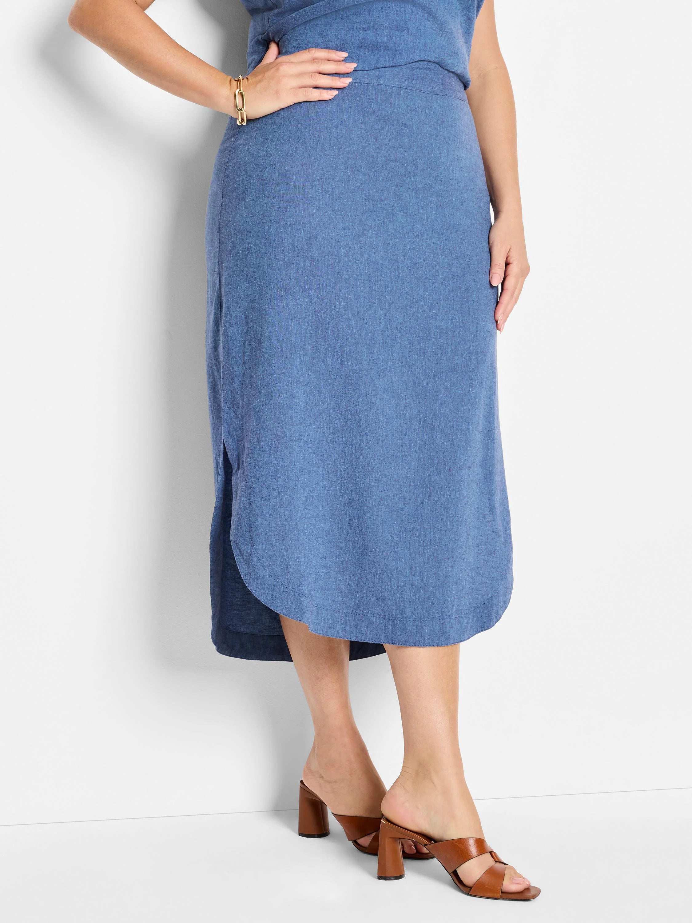 Mid-length denim blue linen skirt, curved hemline, side slits.