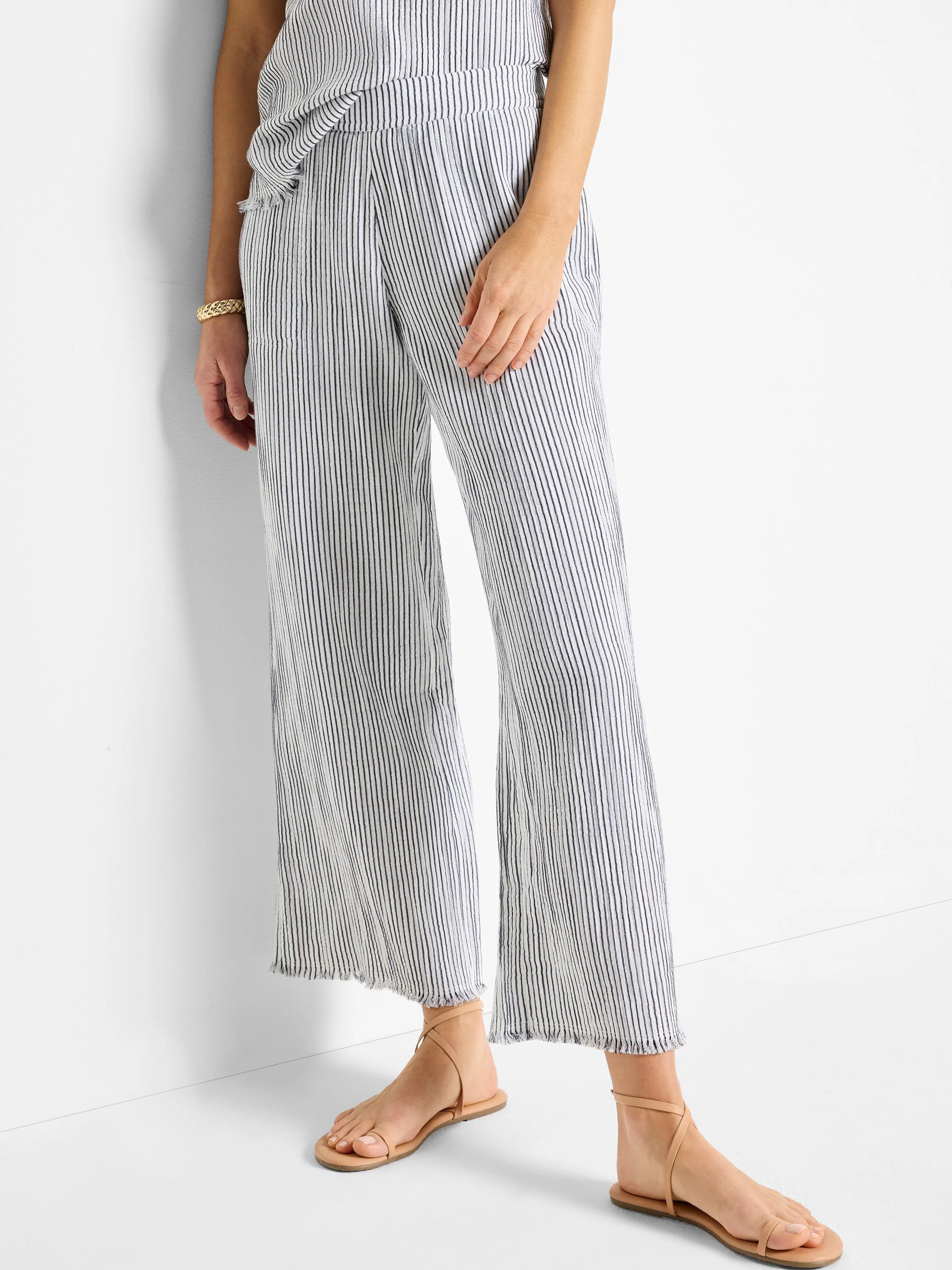 White wide-leg pants with thin navy pinstripes, raw hem.
