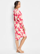 Pink midi dress with beige floral print, belted waist, and long sleeves.
