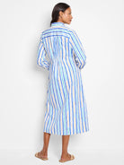 White midi dress with vertical blue, teal, and beige stripes.  Shirt collar, long sleeves, and cinched waist.