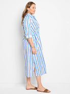 White midi shirt dress with vertical blue, teal, and tan stripes.  Side slits and drawstring waist.