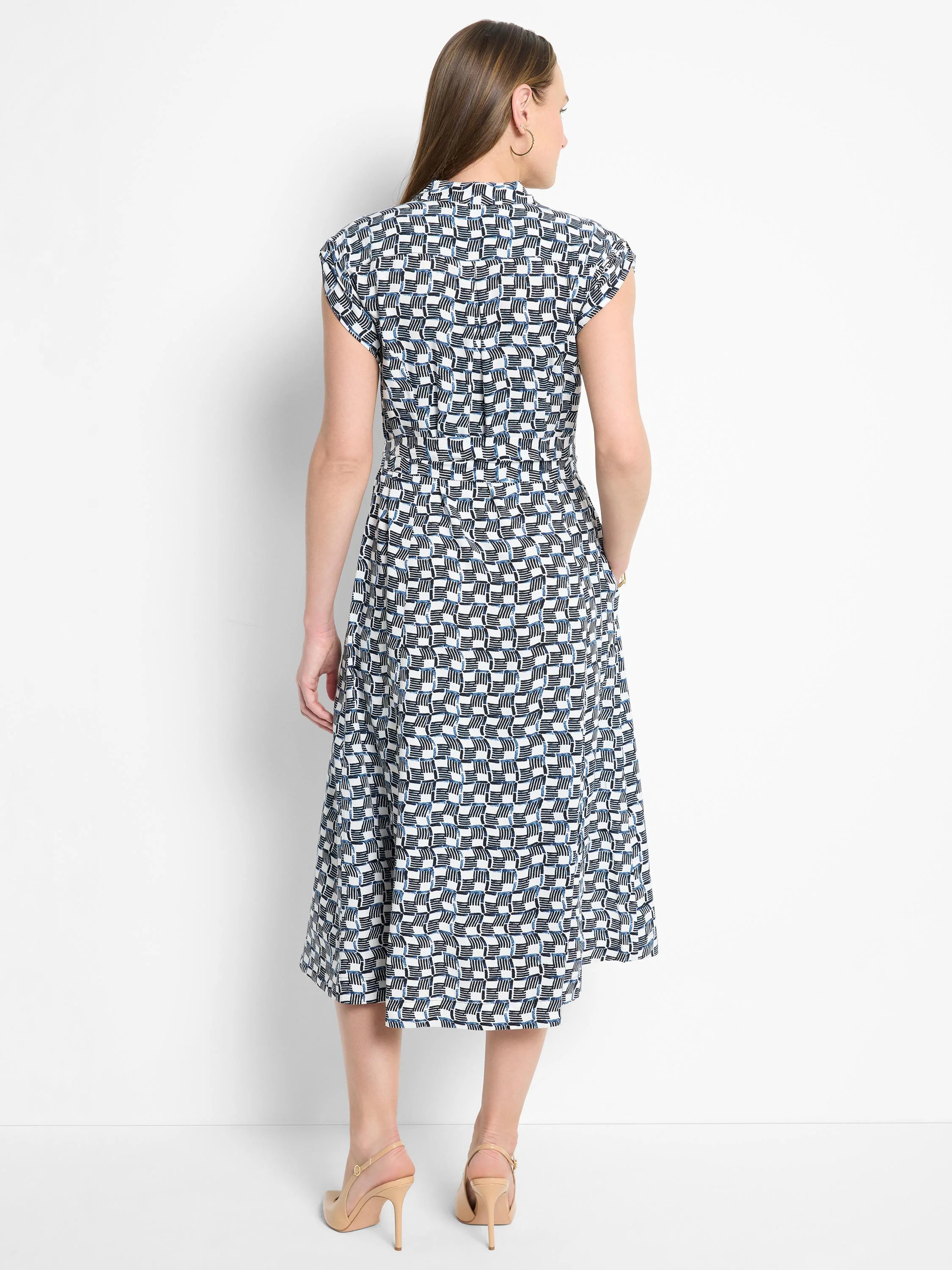 White midi dress with a black and blue geometric pattern, short sleeves, and a cinched waist.