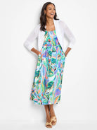 White cropped cardigan over a midi dress with a blue, green, and pink abstract leaf print.