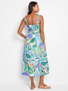 Mid-length sleeveless dress, blue background, vibrant tropical leaf print in greens, oranges, pinks. Square neckline.
