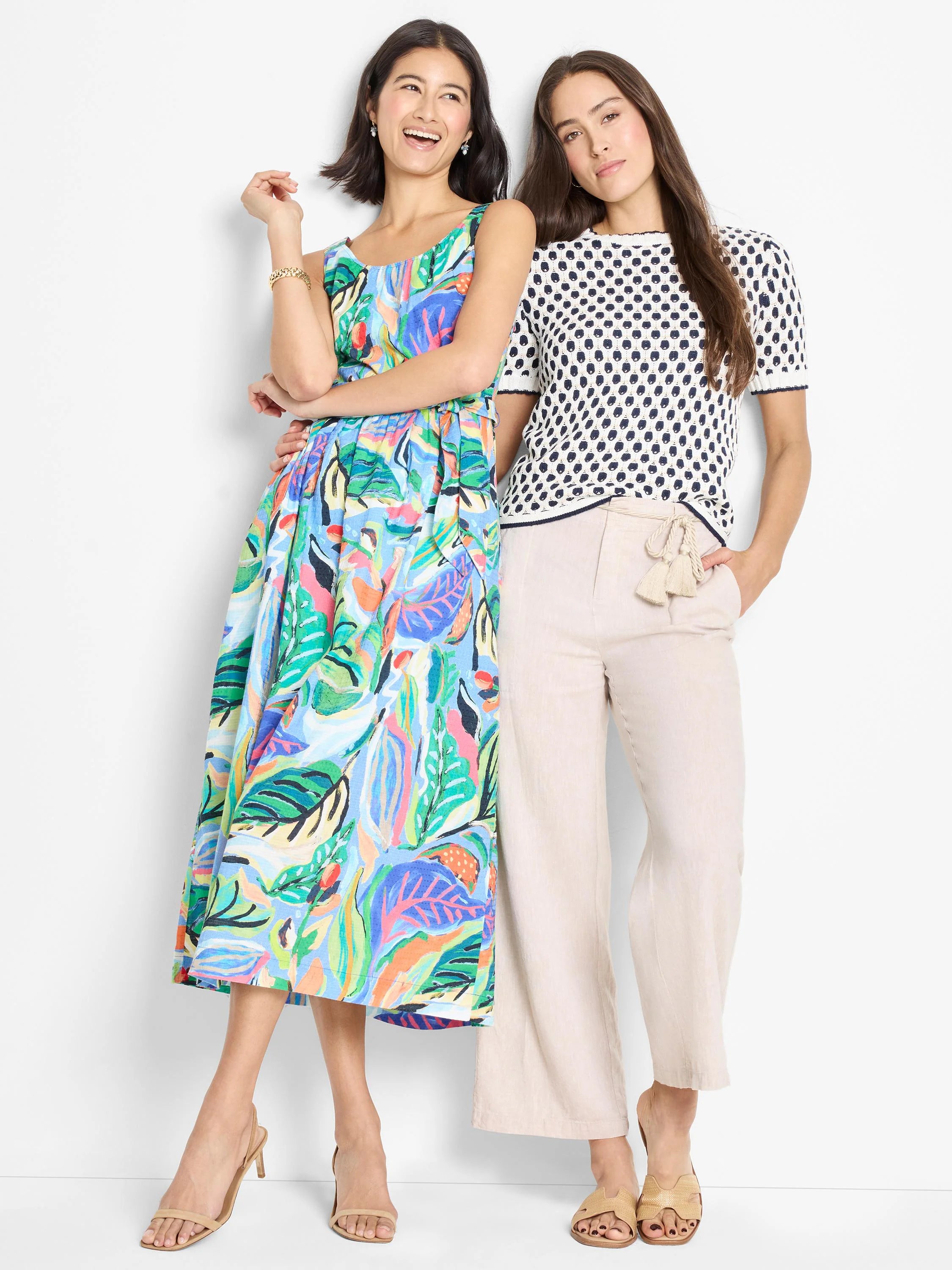 Mid-length sleeveless dress, light blue background with multicolored abstract tropical leaf print.