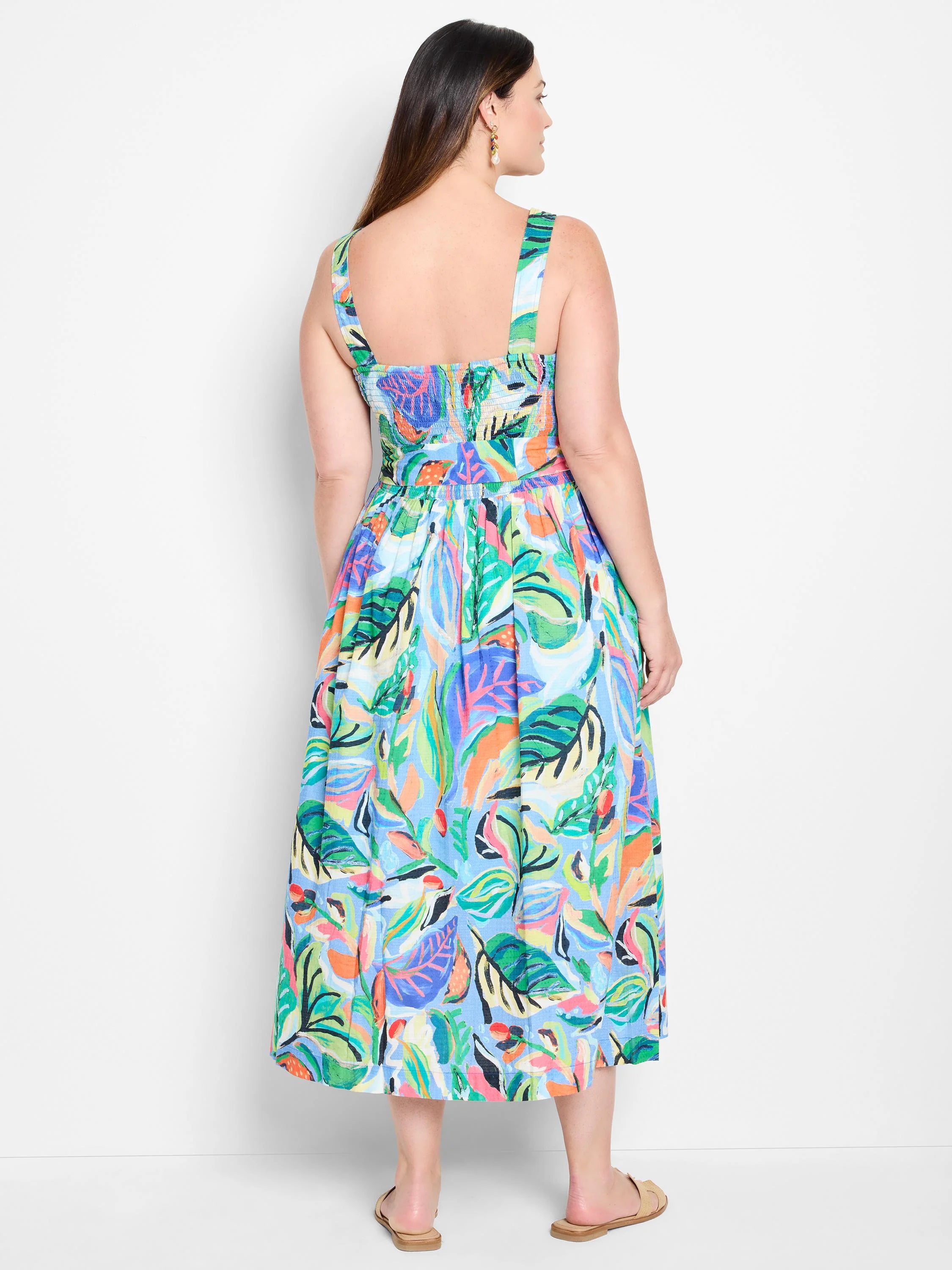 Midi dress, sleeveless,  blue background with green, orange, & purple abstract leaf print.  Square neckline, back view.