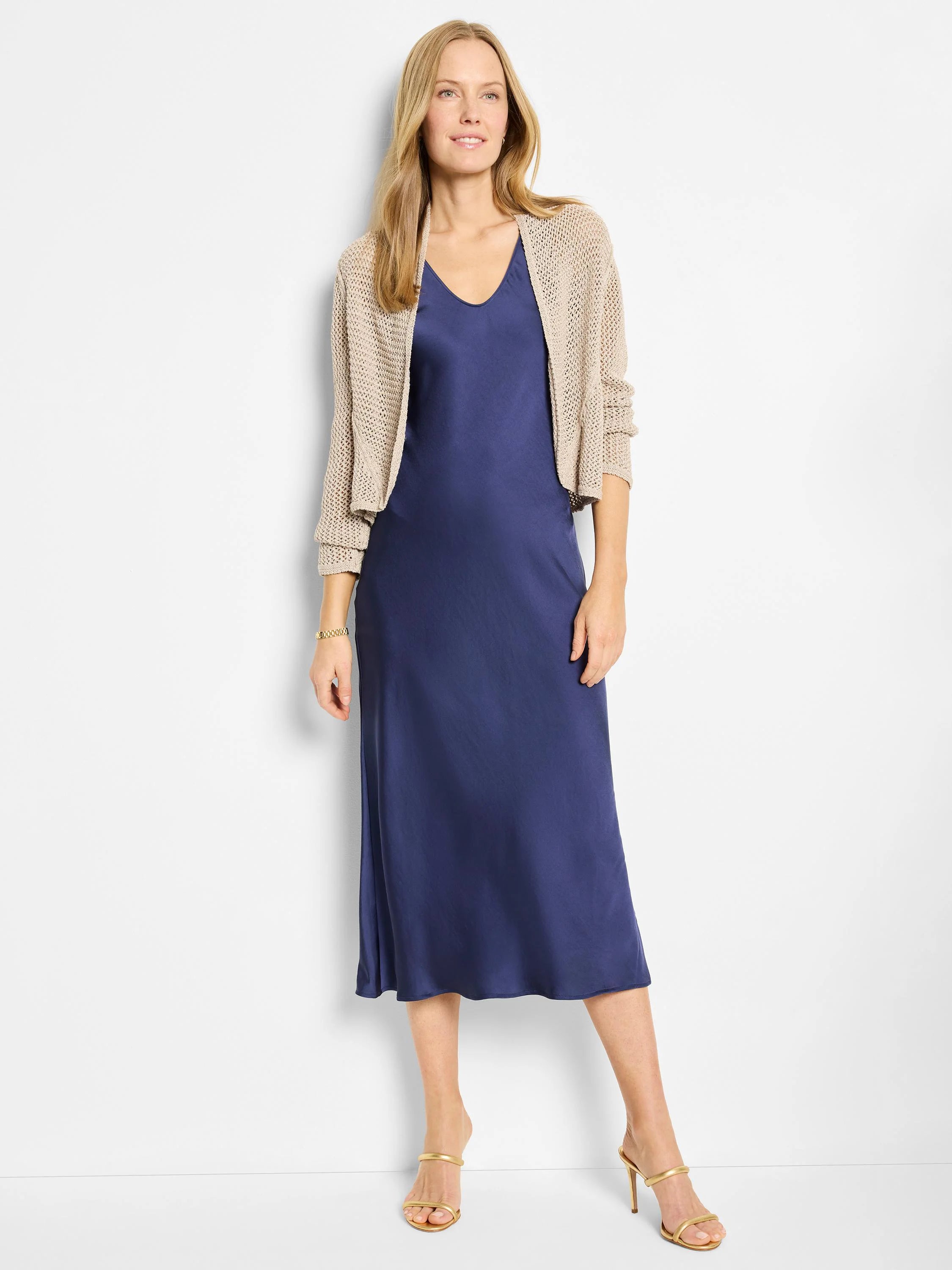 Navy blue bias-cut midi slip dress;  model wears a beige open knit cardigan.
