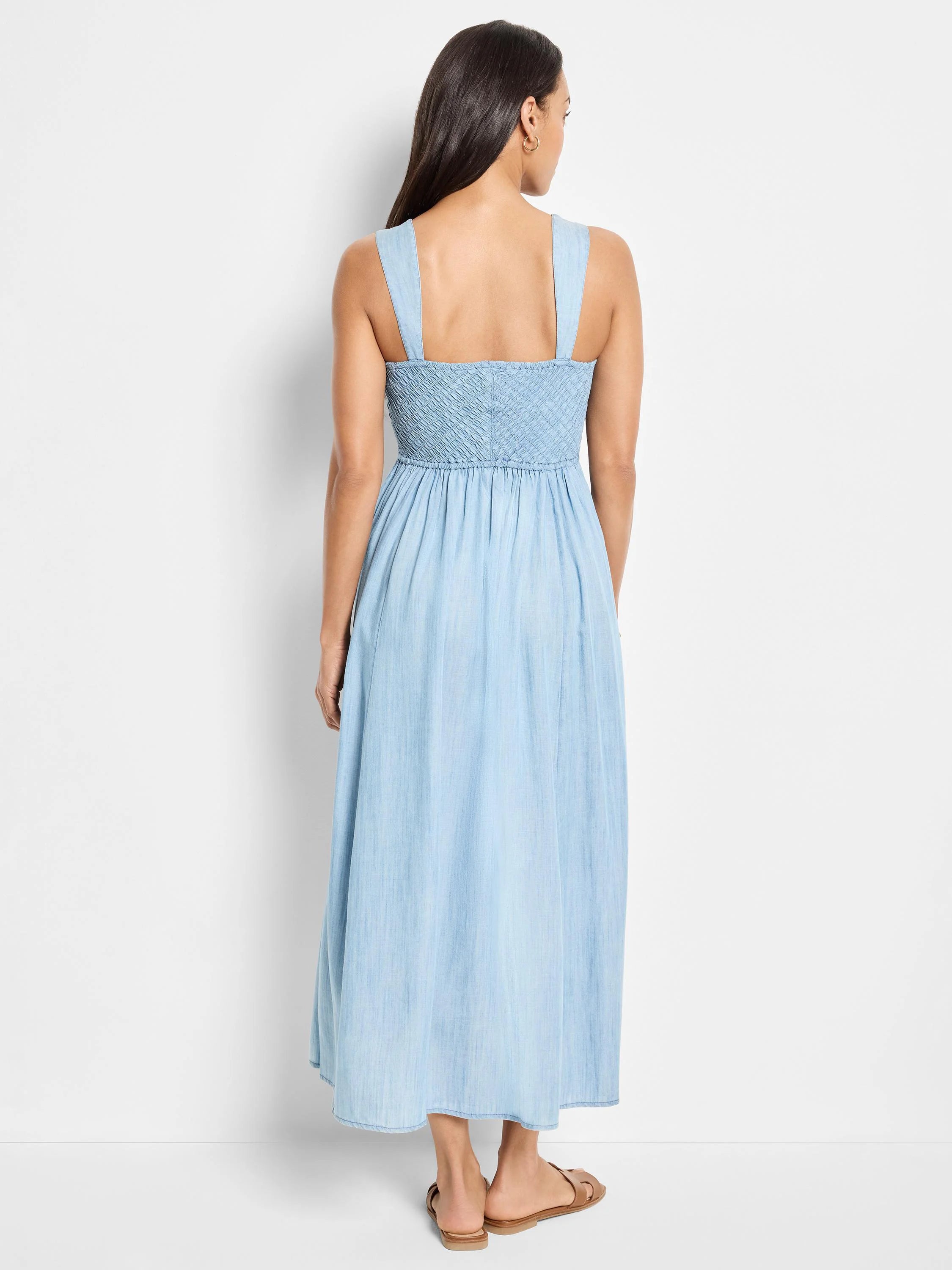 Light blue denim midi dress, sleeveless, square neckline, smocked bodice.  Back view.
