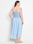 Light blue denim midi dress with smocked bodice and thin straps.  Back view.