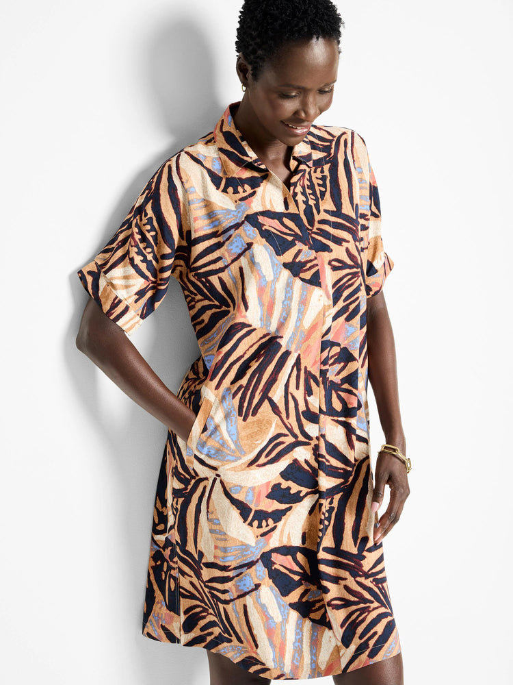 Terracotta shirt dress with short sleeves, featuring a dark-navy, beige, and coral leaf print.  Has pockets.