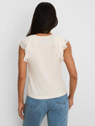 Light cream top, back view, with a round neckline and layered chiffon ruffle sleeves.