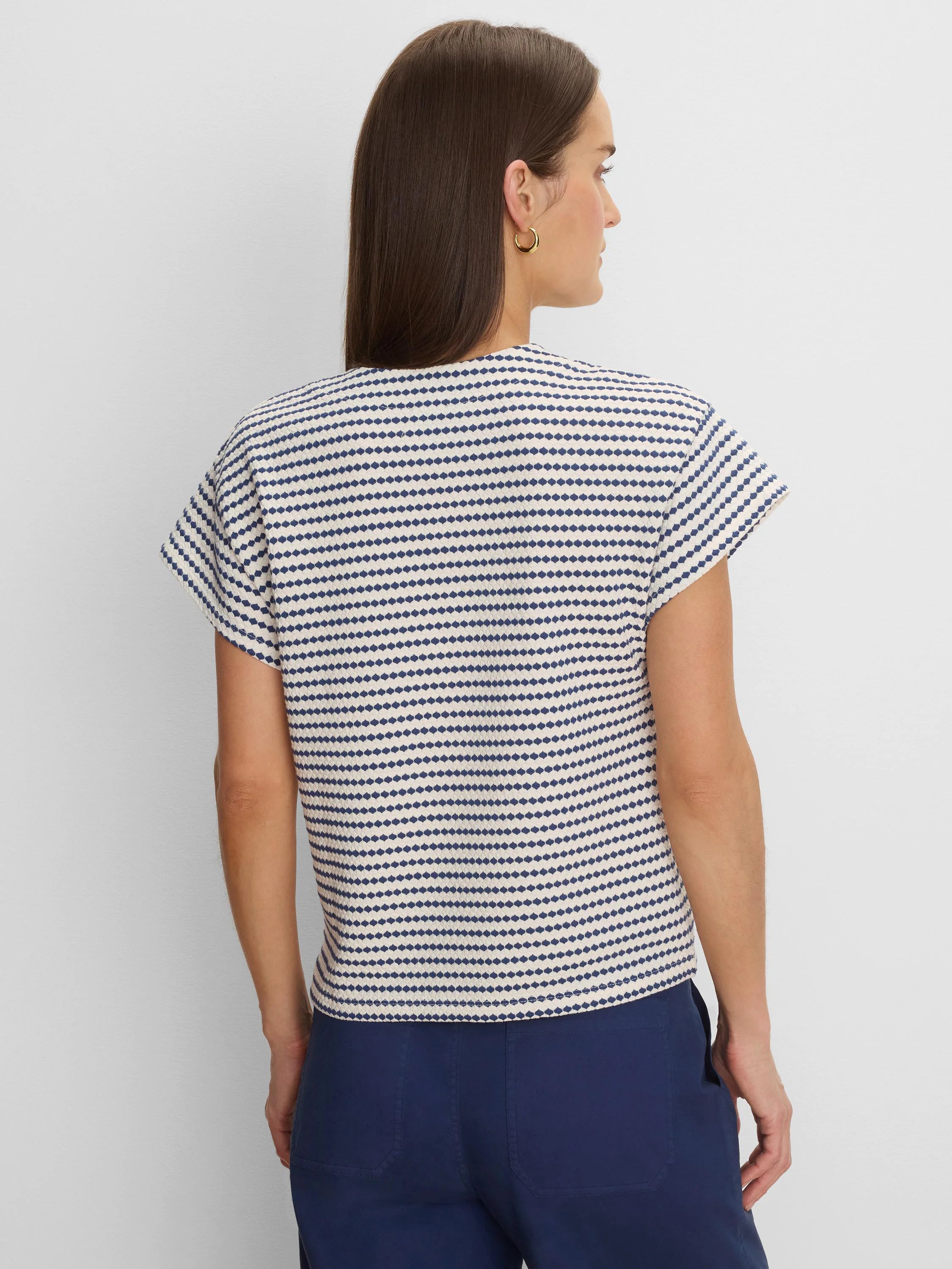 Cream & navy blue top with horizontal stripes made of small, textured diamond shapes. Features short, relaxed sleeves.