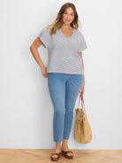 Off-white V-neck top with navy diamond stripes and short sleeves.