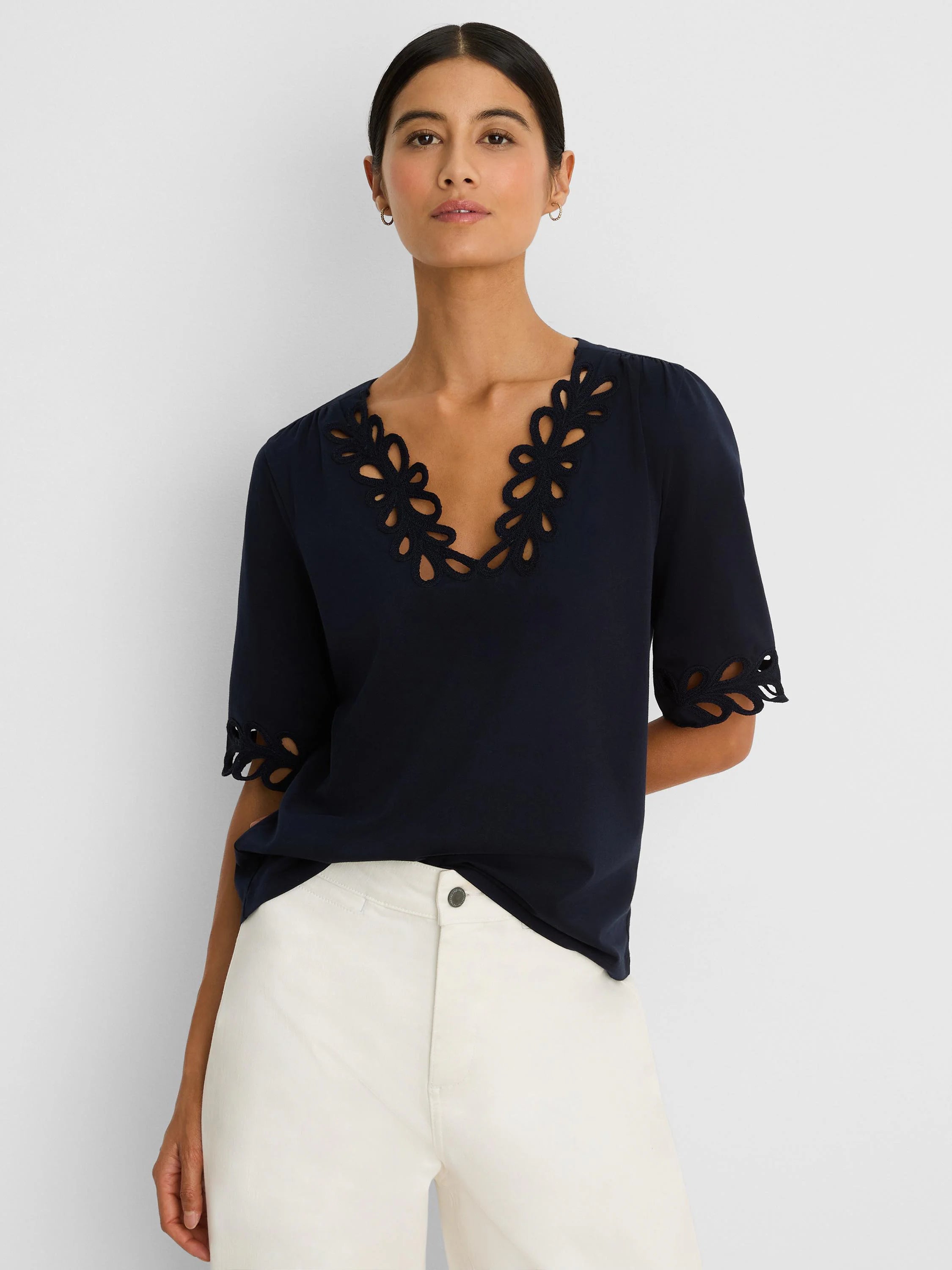 Navy blue top with intricate cut-out V-neck and sleeve edges.