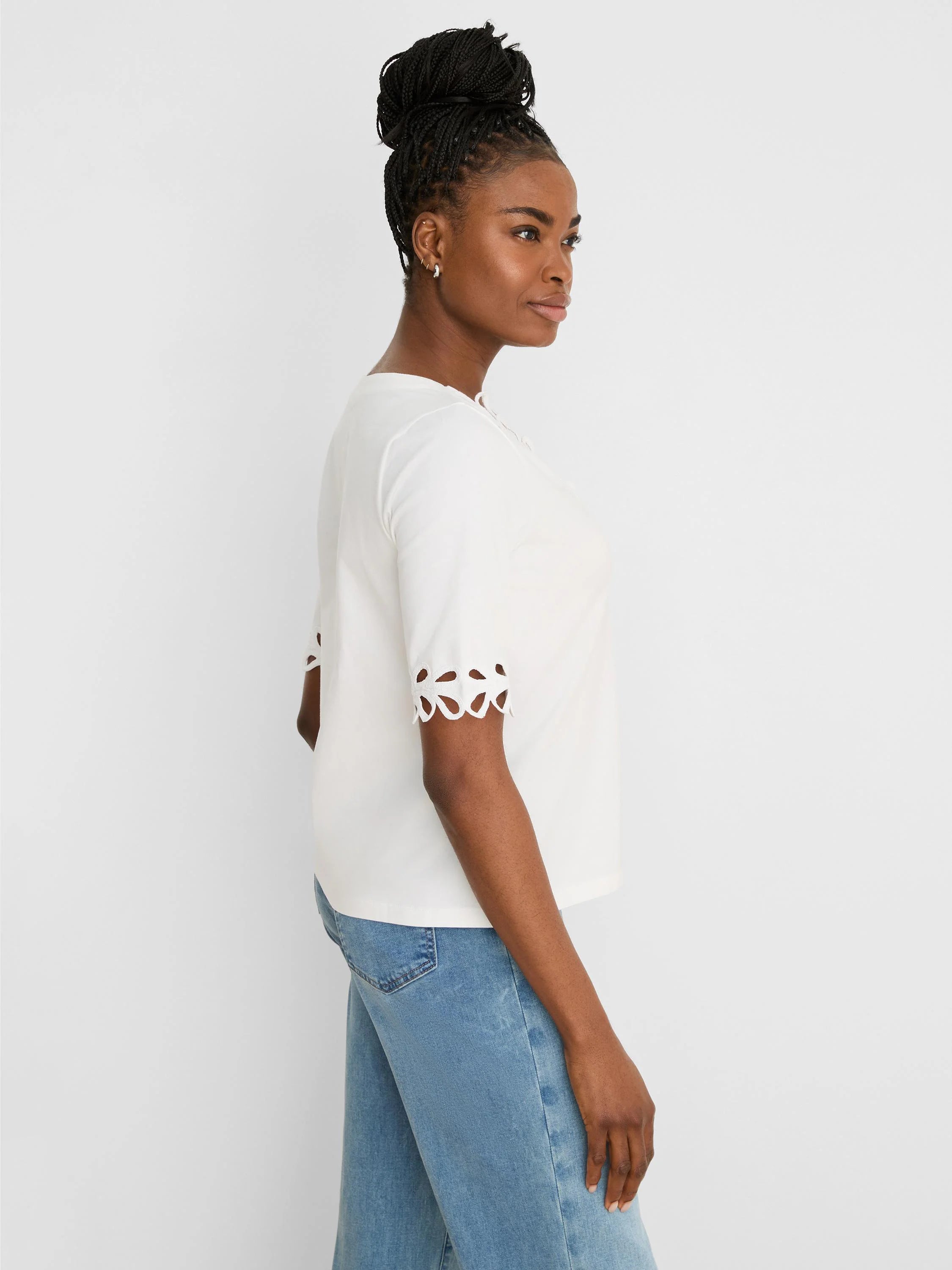 White short-sleeve top with decorative, scalloped cut-out edges on the sleeves.