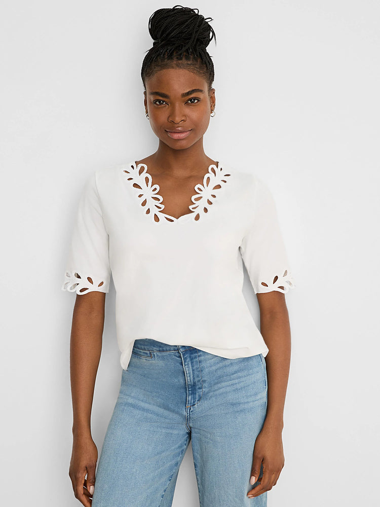 White V-neck top with short sleeves. Floral cutout edges on the neckline and sleeve cuffs.