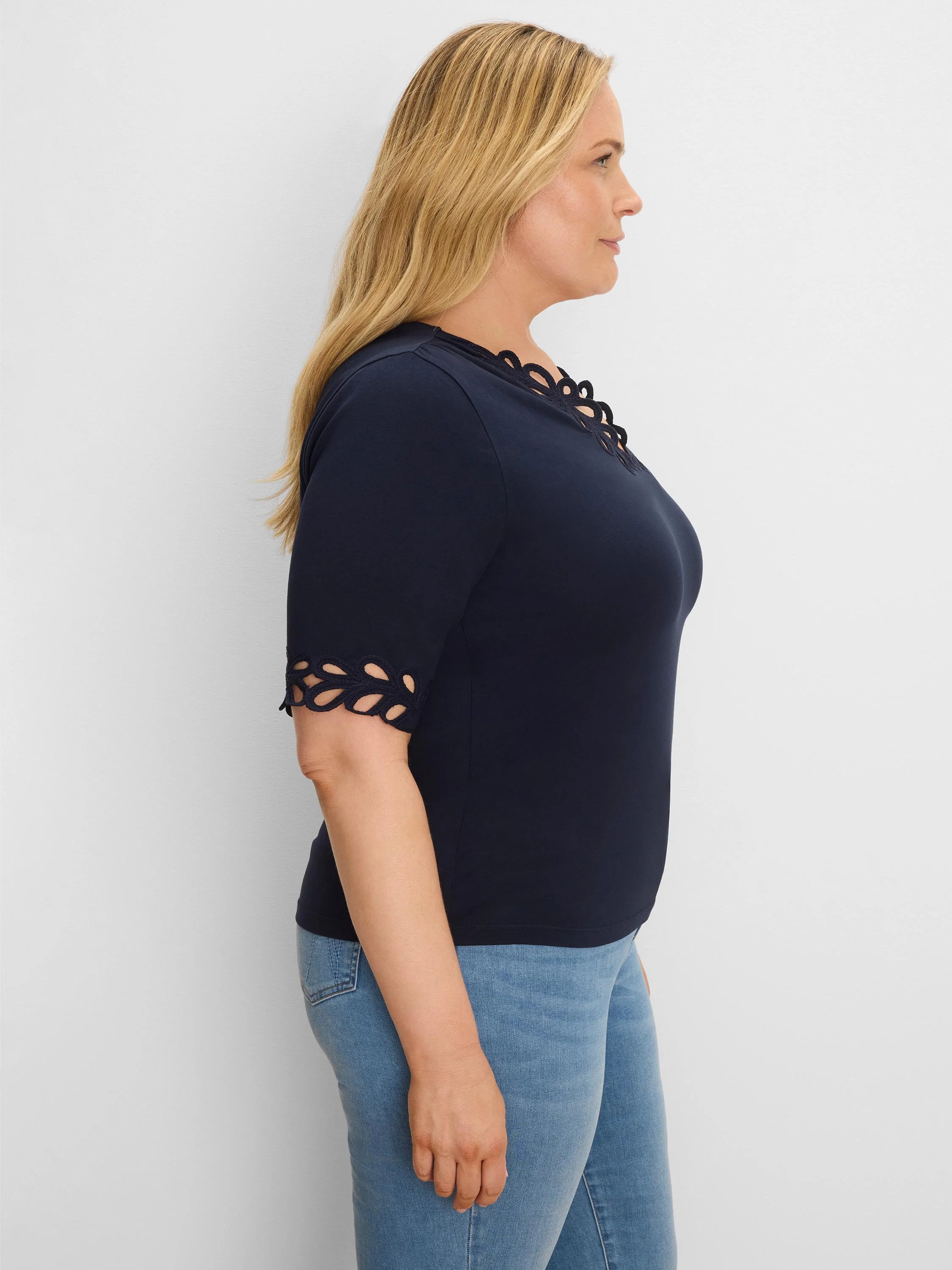Navy top with scalloped cutouts at the neckline and elbow-length sleeve cuffs.