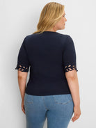 Navy short-sleeved top with leaf-like cut-outs at the sleeve edges, shown on a model from behind.