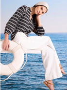 Black knit top with white dotted horizontal stripes, long sleeves, and a v-neck.