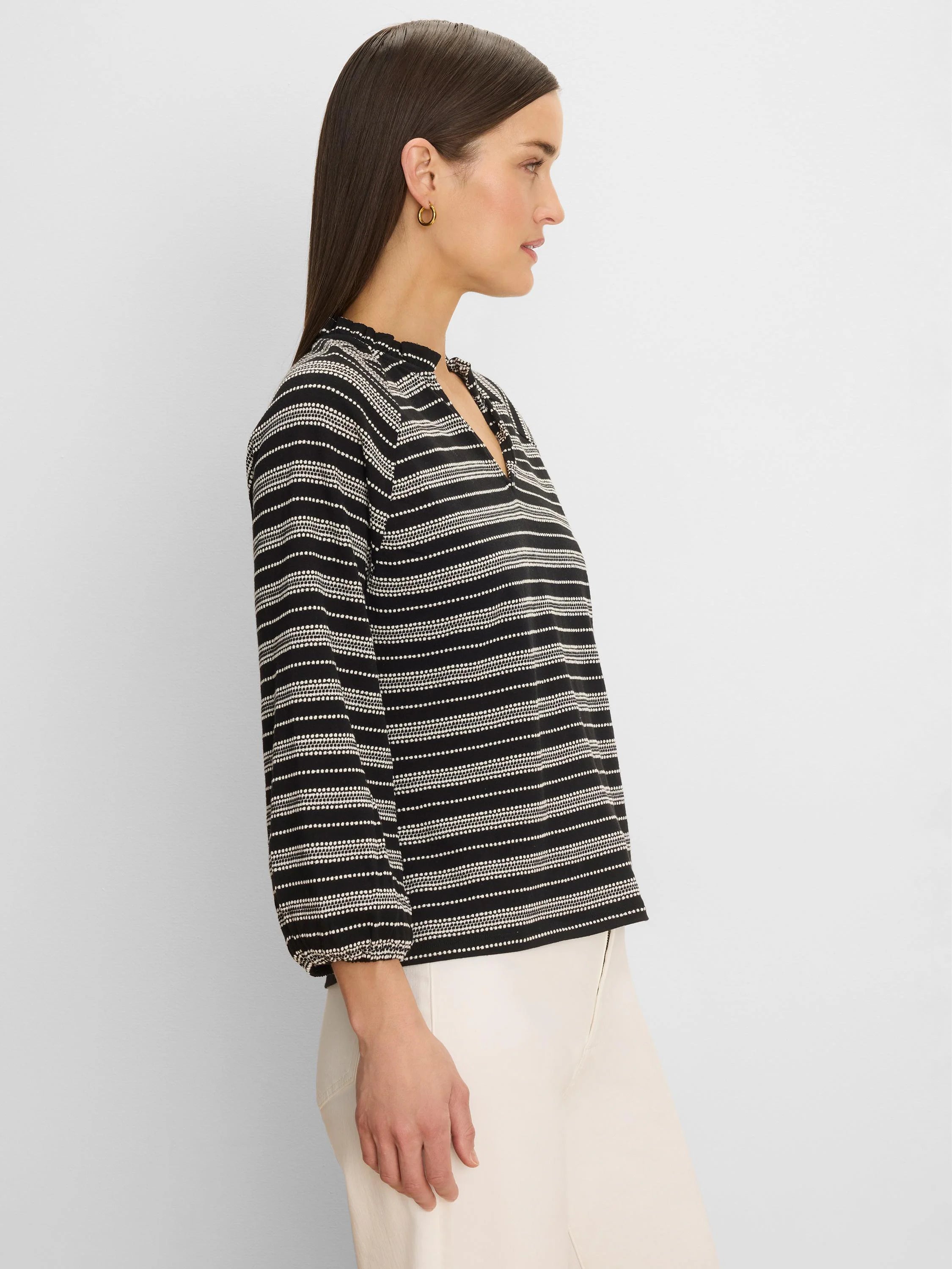 Black & white knit top with dotted horizontal stripes, ruffled high neck, V-slit, and long sleeves.