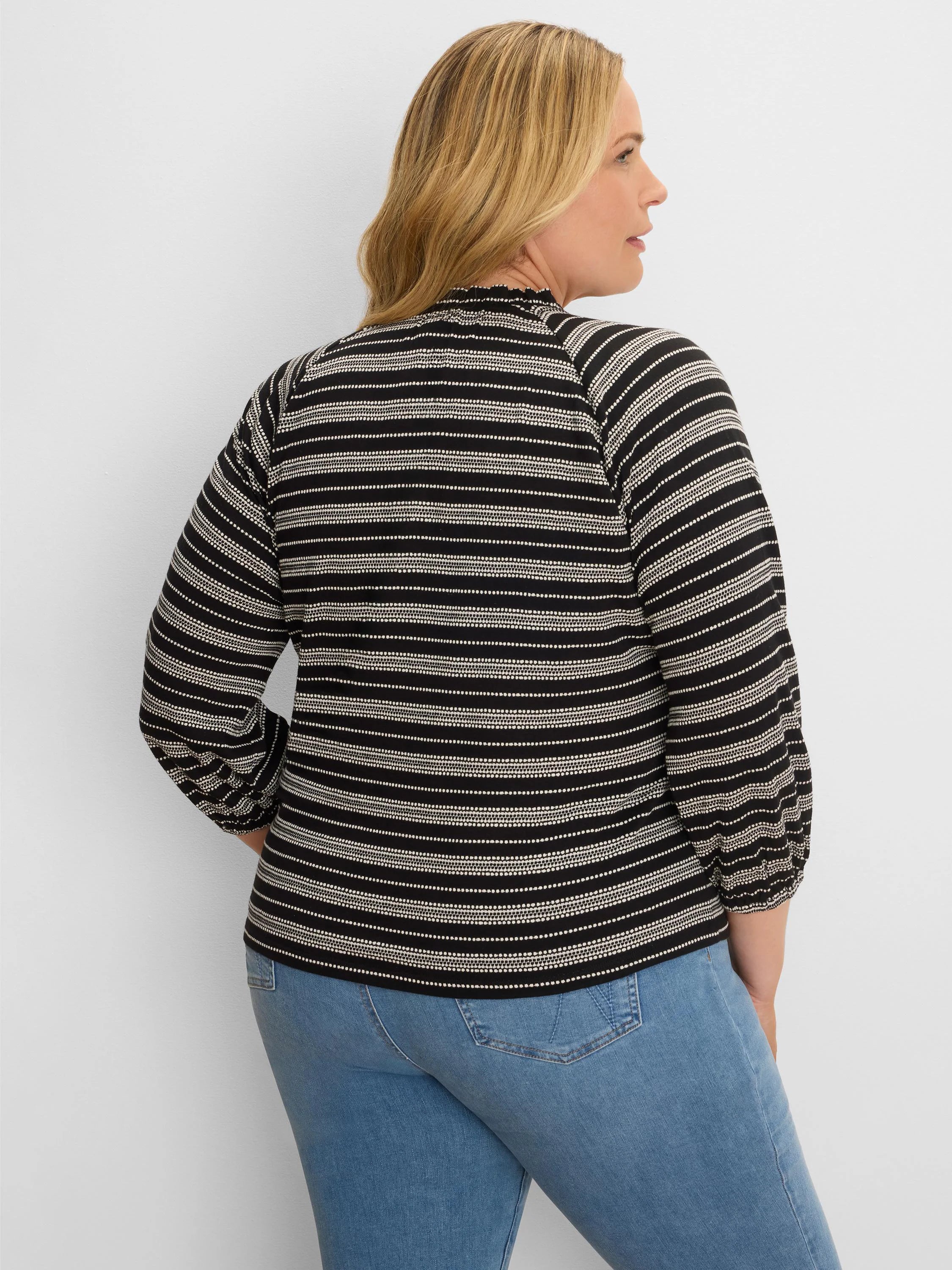 Black & off-white knit top with varied horizontal stripes, ruffled mock neck, and long sleeves with gathered cuffs.