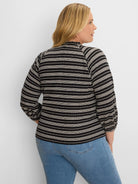 Black & off-white knit top with varied horizontal stripes, ruffled mock neck, and long sleeves with gathered cuffs.