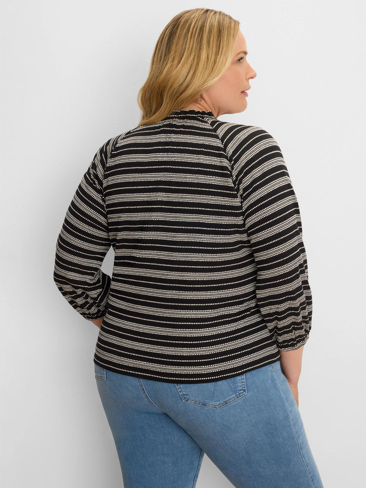 Black & off-white knit top with varied horizontal stripes, ruffled mock neck, and long sleeves with gathered cuffs.