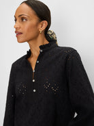 Black knit top with all-over eyelet pattern, ruffle neck, and white button-down placket.