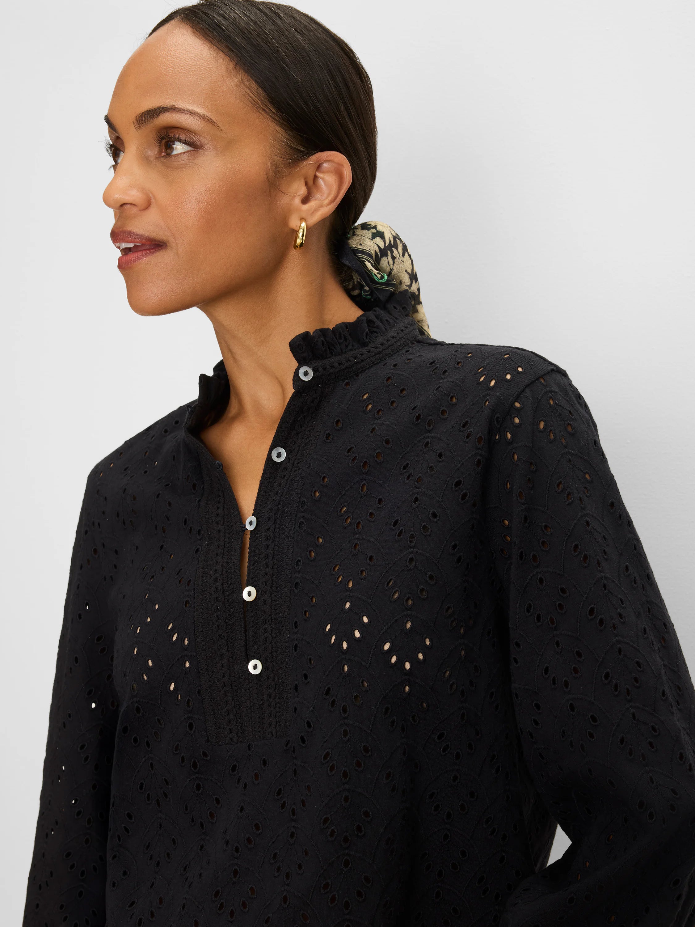 Black knit top with all-over eyelet pattern, ruffle neck, and white button-down placket.