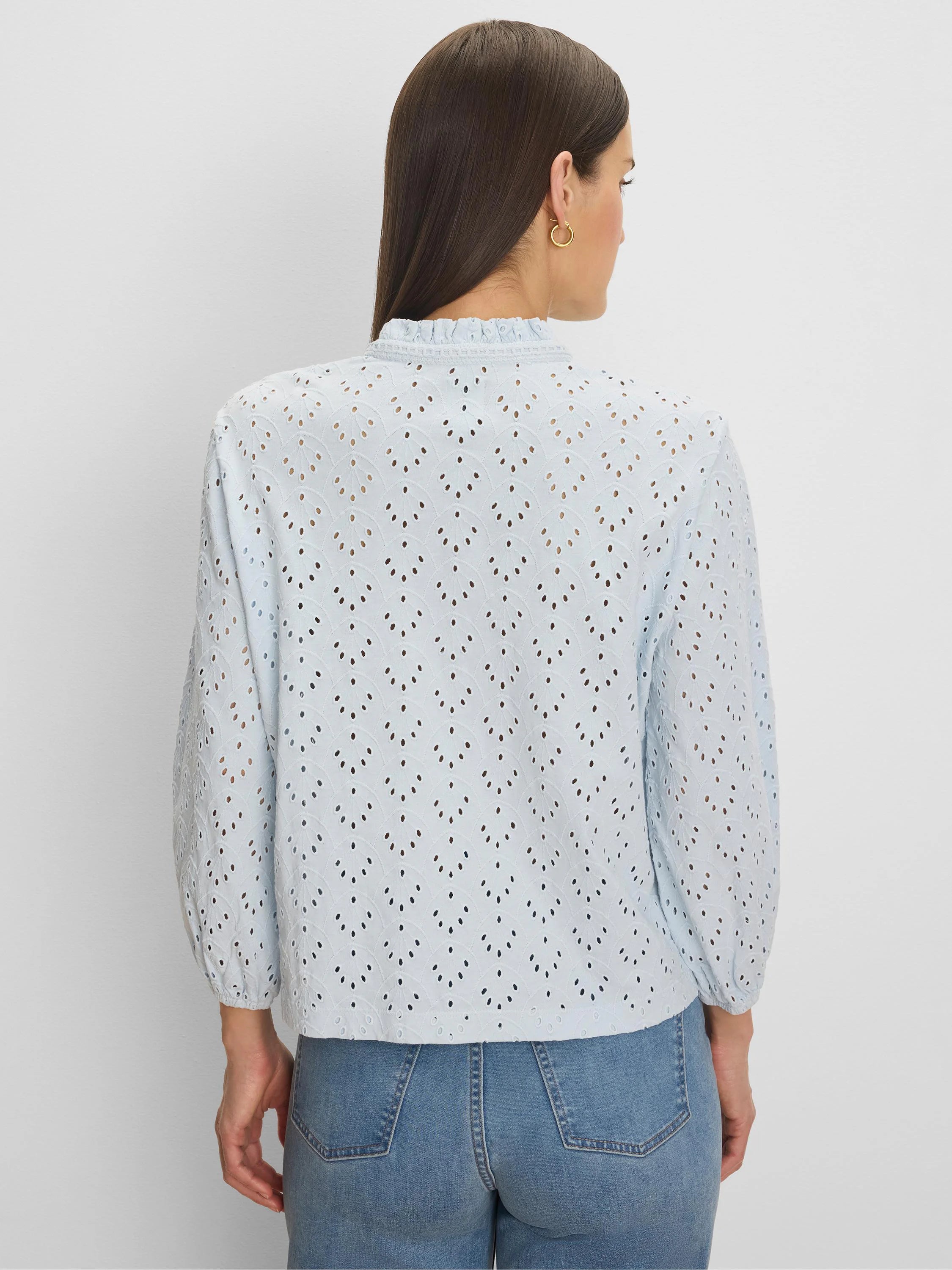 Light blue eyelet top with a ruffle neck, featuring a scalloped eyelet pattern and long sleeves.