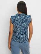 Dark blue & white shibori-patterned top with a ruffled mock neck and ruffled cap sleeves, shown from the back.