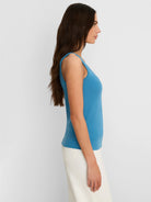 Medium blue, ribbed knit scoop neck tank top on a woman. It has a fitted silhouette.