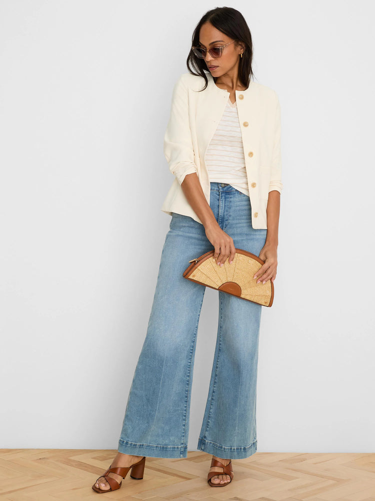 Cream collarless jacket with tan front buttons, two patch pockets, and a sleek fit.