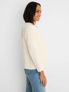 Cream collarless jacket with long sleeves, featuring a smooth finish.