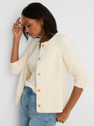 Ivory collarless jacket with tan button-front closure and two front patch pockets.