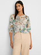 Cream boat neck sweater with an all-over pattern of muted pressed flowers in shades of green, blue, and rust.