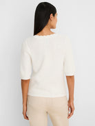 Back view of an off-white scallop-textured sweater tee. Features elbow-length sleeves and a scalloped neckline.