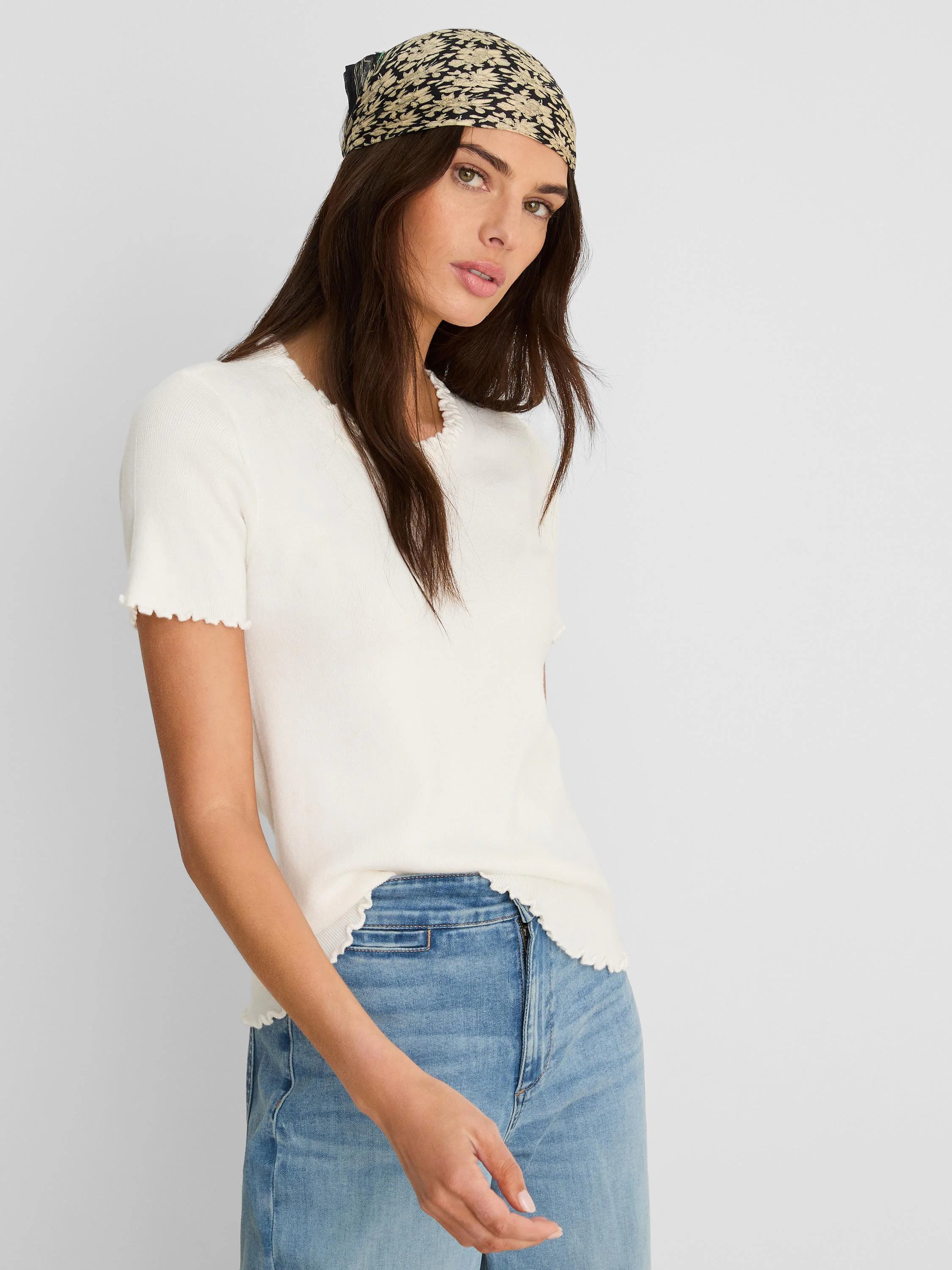 Off-white ribbed short-sleeve tee with ruffle trim at neck, sleeves, and hem.