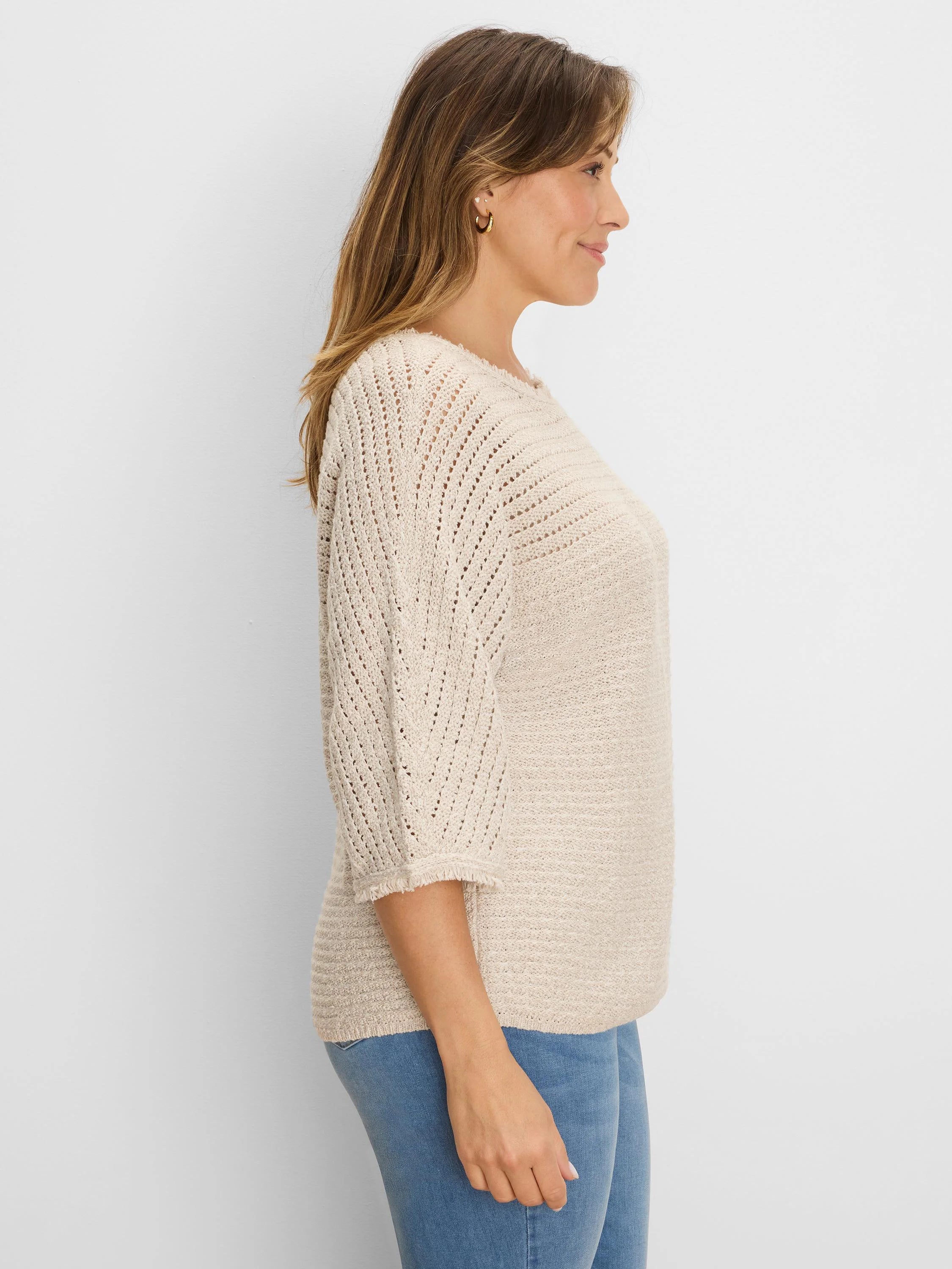 Cream-colored sweater with textured knit body and open-knit chevron 3/4 sleeves, featuring frayed cuffs.