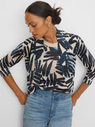 Bolero cardigan, beige knit with 3/4 sleeves, featuring a shimmering abstract dark blue and black palm print.