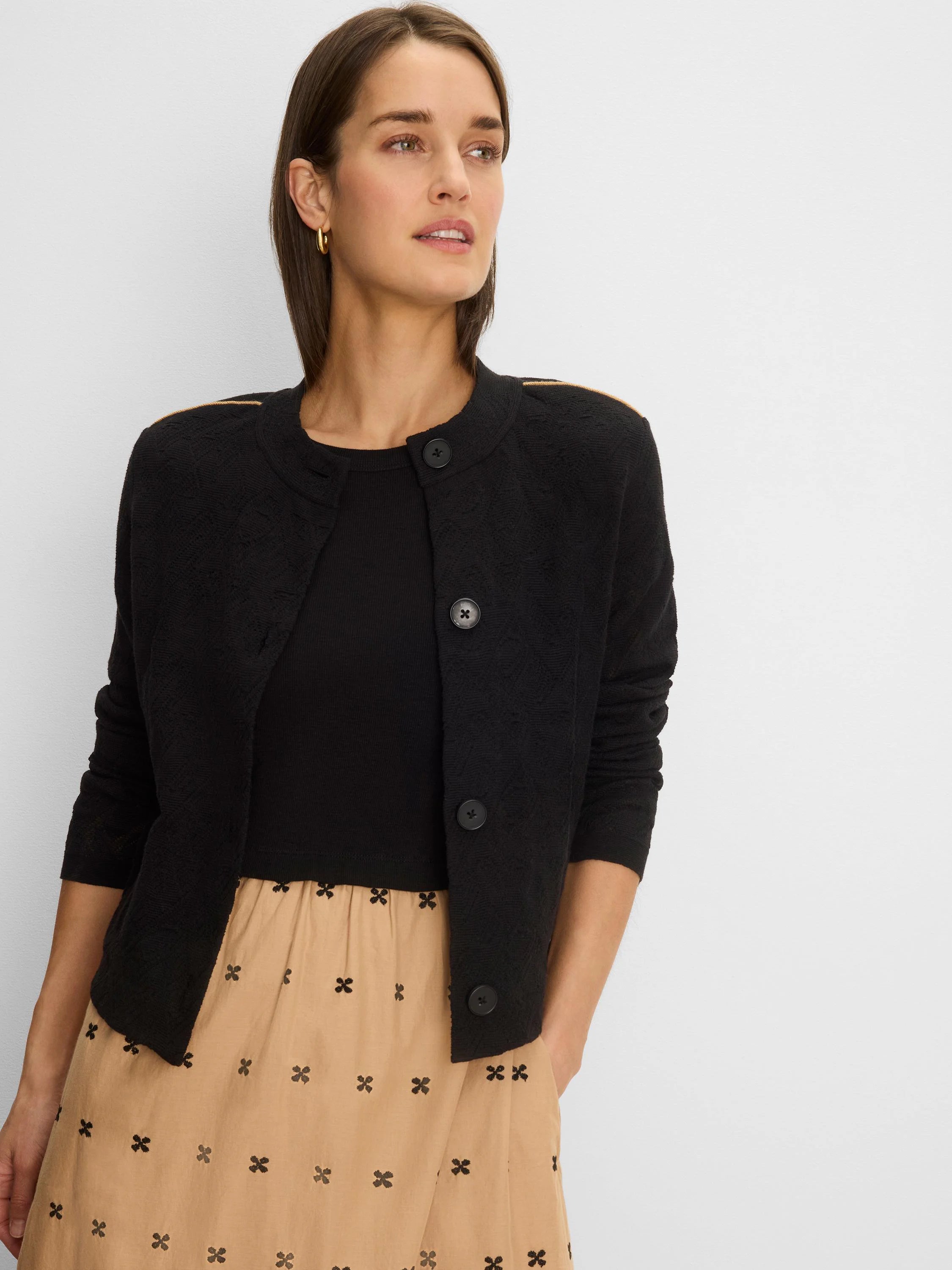 Black knit jacket with geometric texture & tan piping along shoulders. Round neck, black buttons.