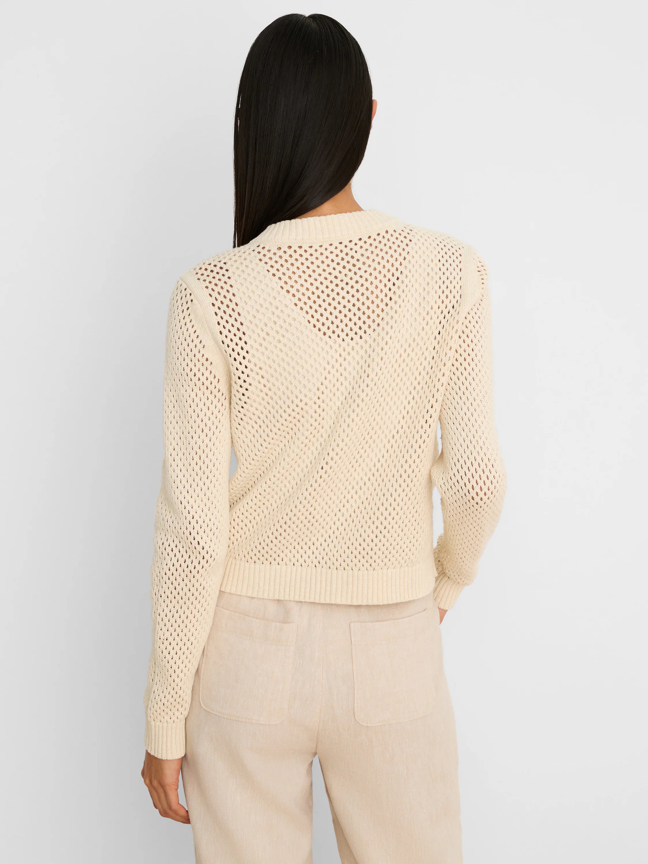 Cream open-knit cardigan shown from the back, featuring ribbed cuffs and hem.